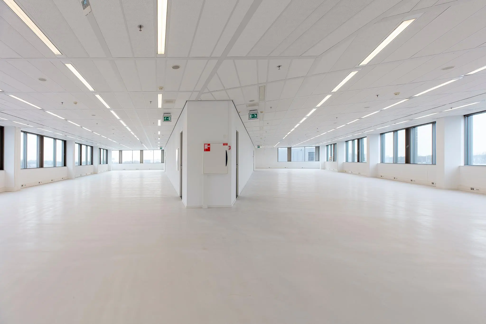 Licht en ruim leeg kantoorpand aan de Vliegend Hertlaan met grote raampartijen en witte vloer.